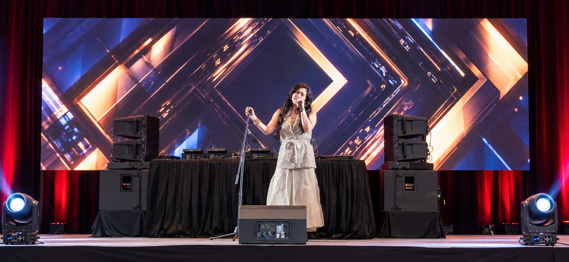 Live vocalist on stage with an LED video wall, line array speakers and moving head lights at a 500 guest client appreciation gala produced by W Square