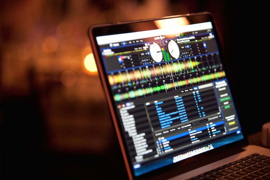 DJ Love's laptop running Serato at a live event, with the track library and waveforms on screen