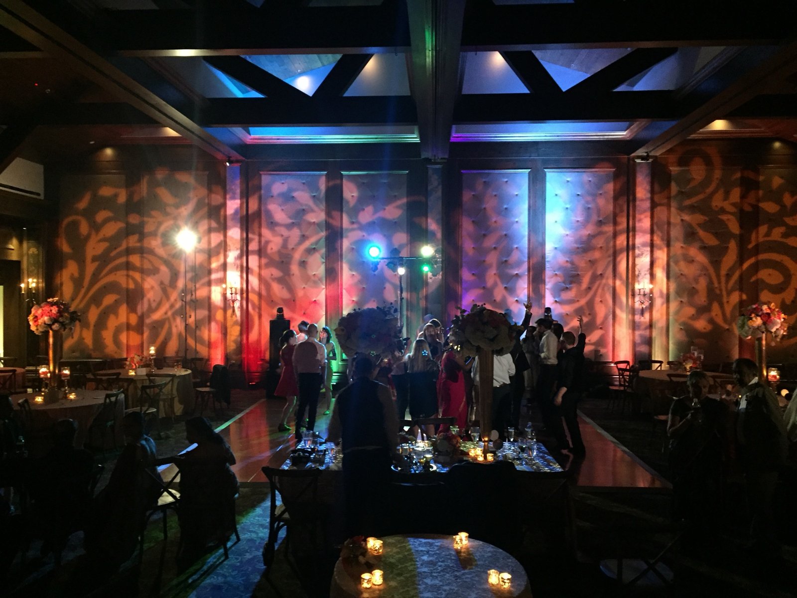 Custom damask gobo patterns across ballroom walls with color uplighting during a wedding reception